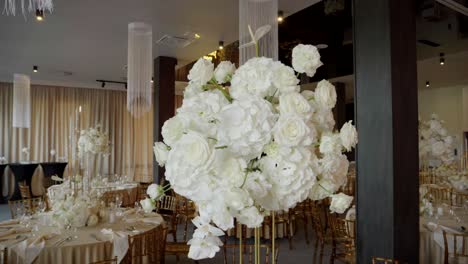 beautifully decorated elegant round tables in a wedding hall, featuring large bouquets of beautiful flowers
