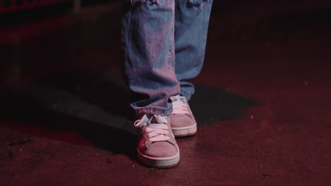 young beautiful woman in sneakers and ripped jeans on the street at night