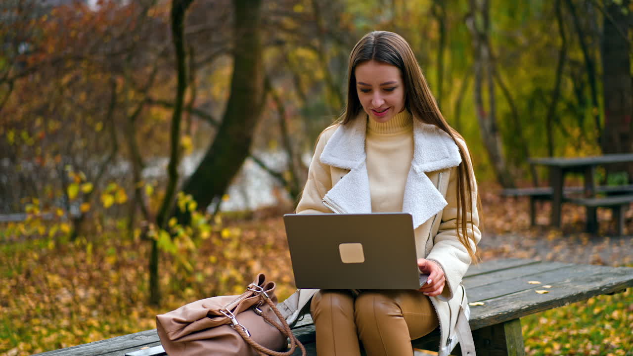 Woman having a video call in an autumn park