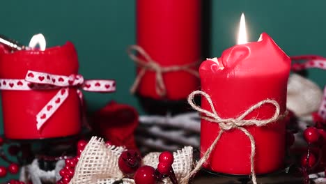 lighting candles on modern christmas wreath with four red candles on wooden surface with green background, holiday interior design, panning shot right to left