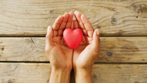 video of close up of heart and hands on wooden background