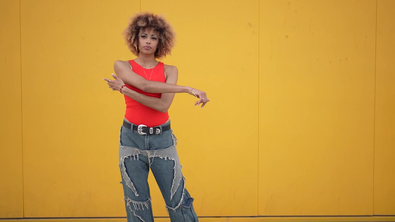 Stylish young woman posing confidently in front of a bright yellow wall with flair