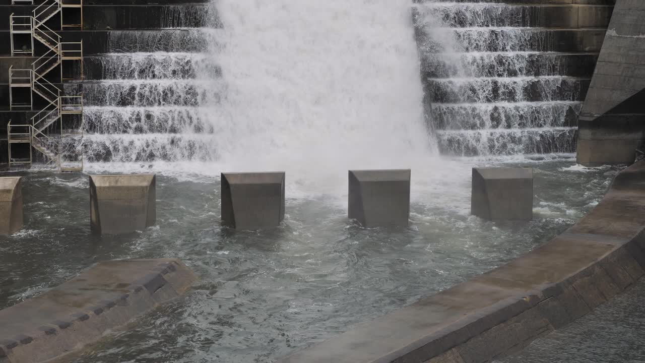 Tight view of water flowing through the bottom of the Hinze Dam overflow and dam steps due to ongoing heavy rains in the Gold Coast Hinterland