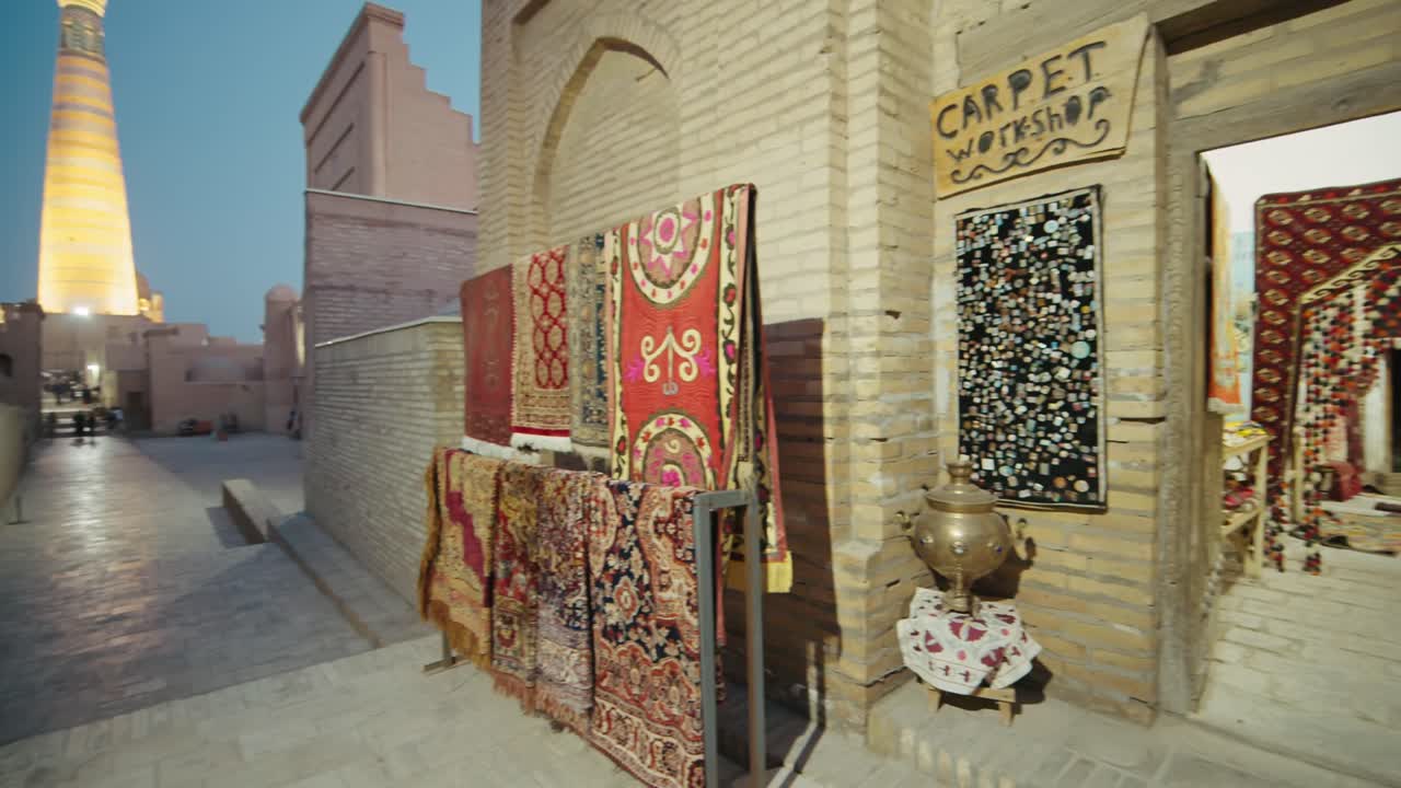 Khiva night time carpets store old city minaret and mosque beautifully illuminated, Uzbekistan silk road at night