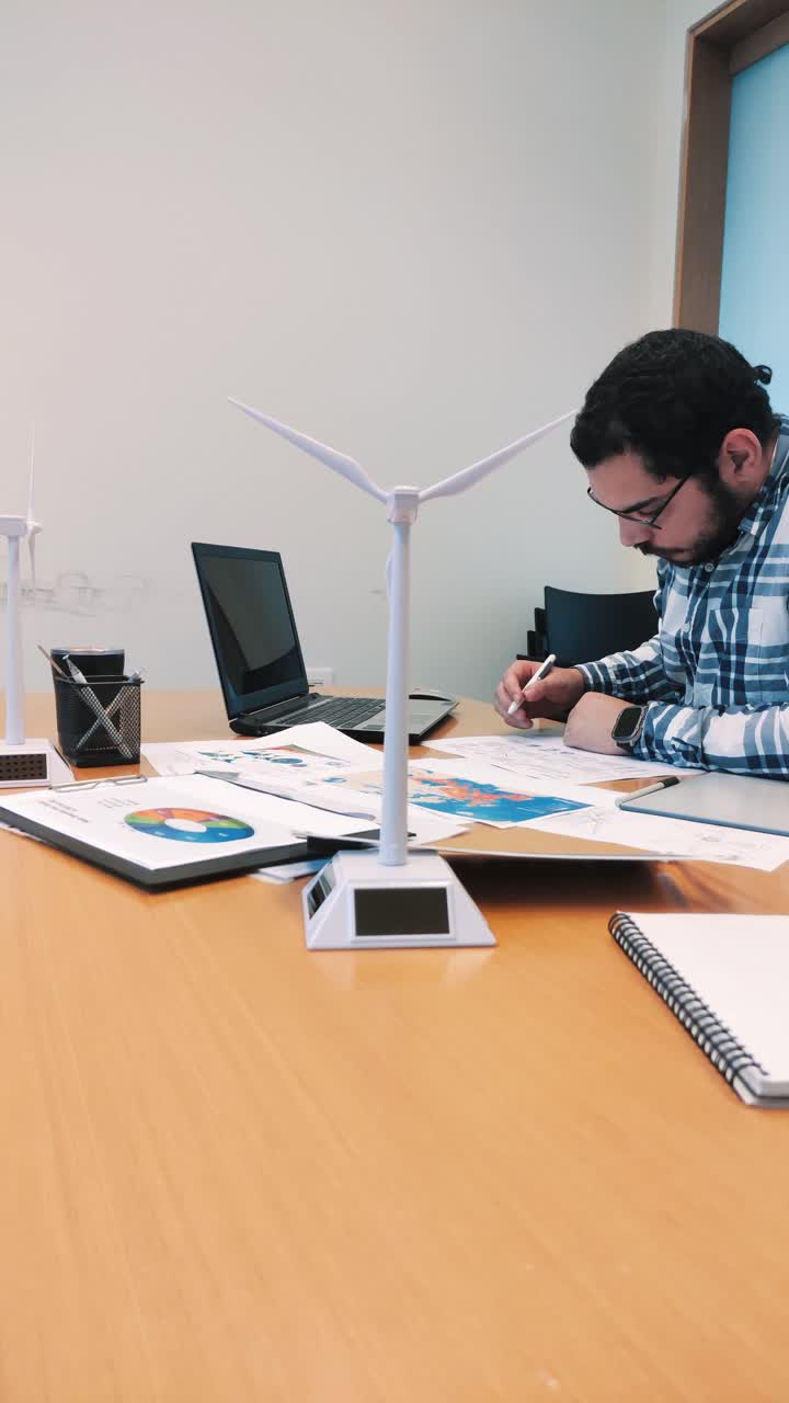 Male Architect Cross-Referencing Documents for a Sustainable Project