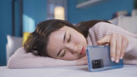 tired asian young woman sleepy using phone.