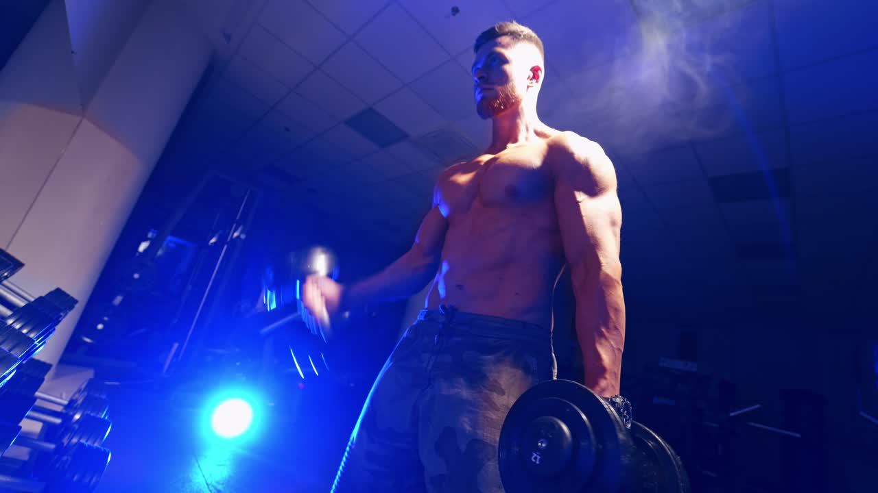 Man training in a gym. Fit young man in sportswear focused on lifting a dumbbell