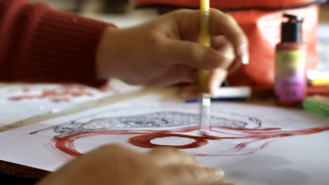 Close-Up of Hand Painting Red Design on Paper with Brush