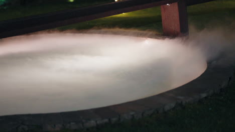 Mystical-dry-ice-fog-flowing-over-pool-edge-at-night