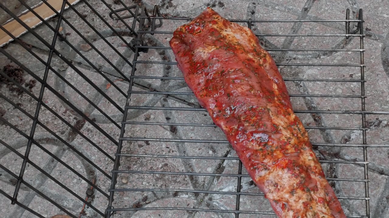Costine crude condite poste su un cestello per griglia in metallo all'aperto per la preparazione del barbecue