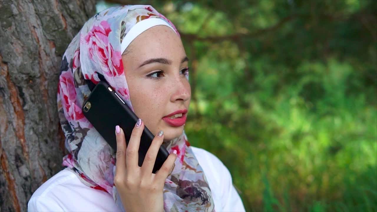 Wanita muda berhijab menelepon di taman