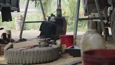worker repairing heavy construction equipment in a shed