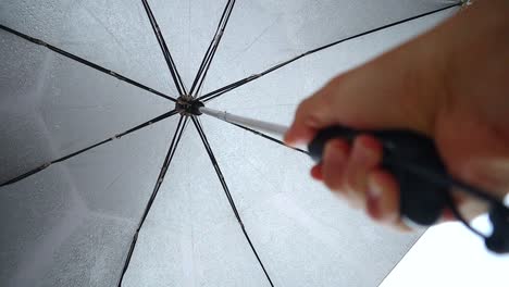 person holding an umbrella during a heavy rain, shot from the bottom up