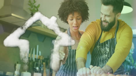 animation of cloud house icon over happy diverse couple cooking in kitchen