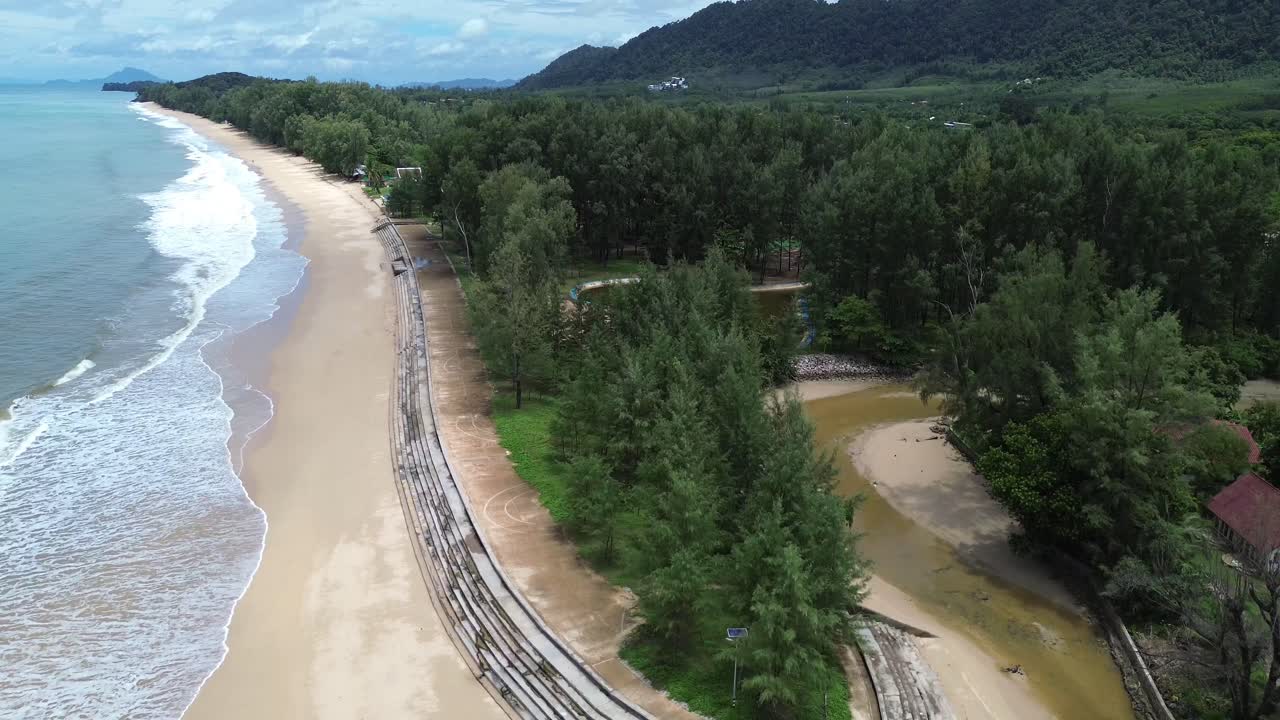 Aerial drone footage of Phra Ae Public Health Park in Koh Lanta, Thailand, showing lush green landscape, walking paths, tropical trees and scenic coastline with beautiful beach