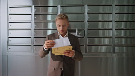 successful man checking post in office building. handsome guy looking letters