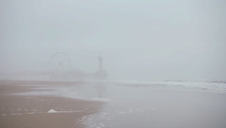 view of an amusement park next to the ocean, during a super foggy day in den haag