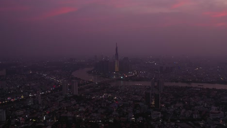 Vista-Aérea-De-La-Ciudad-De-Ho-Chi-Minh-Y-El-Río-Saigón-En-El-Crepúsculo-Con-Luz-Ambiental-Y-Artificial