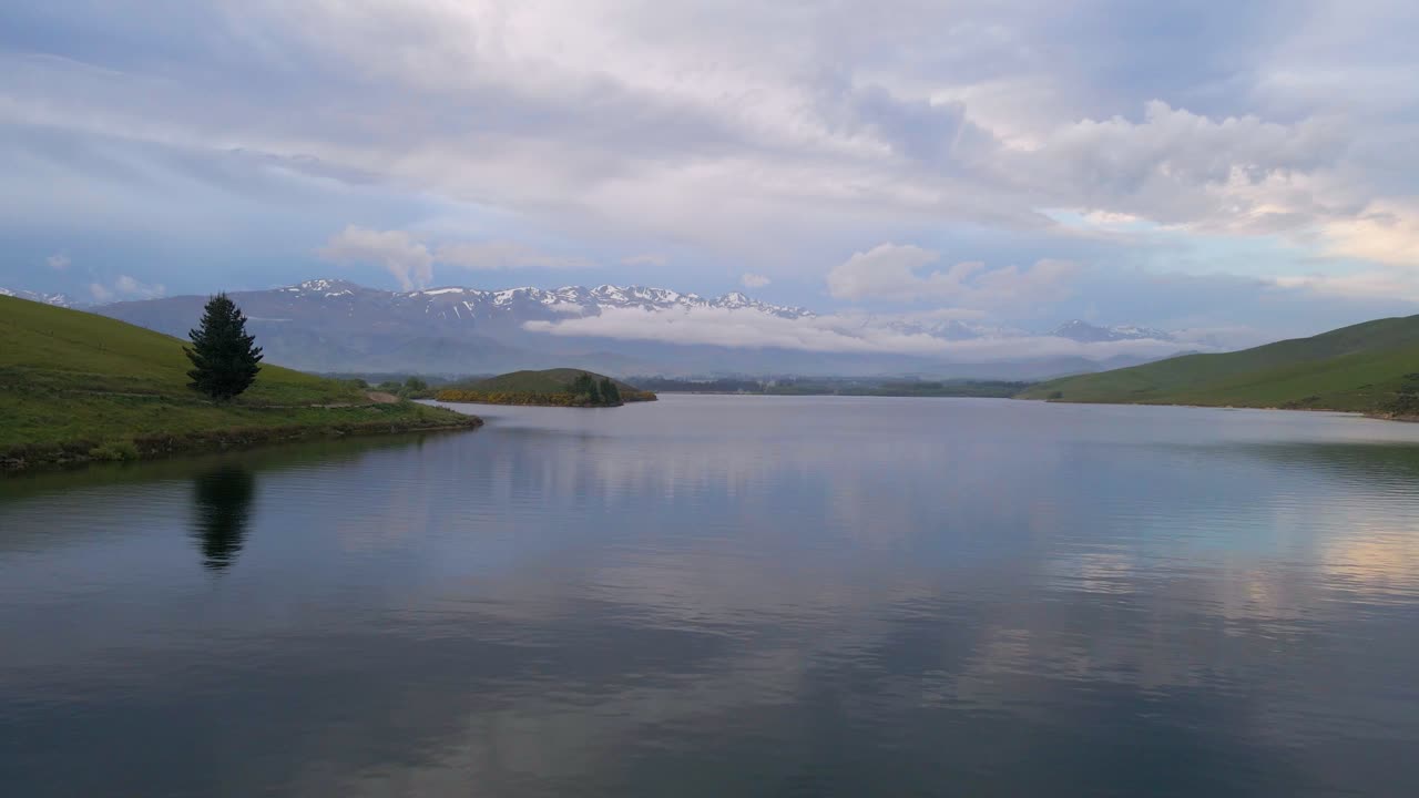 синий час на озере опуха с одиноким деревом на берегу и заснеженными горами на заднем плане