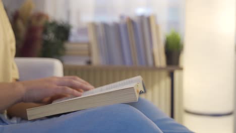 leyendo un libro. hombre leyendo con la mano y volteando la página por la noche en casa.