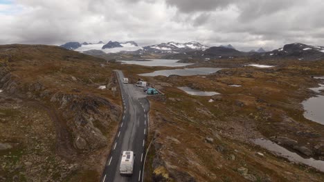 aerial shot of a road through the norwegian mountains, surrounded by lakes and nature