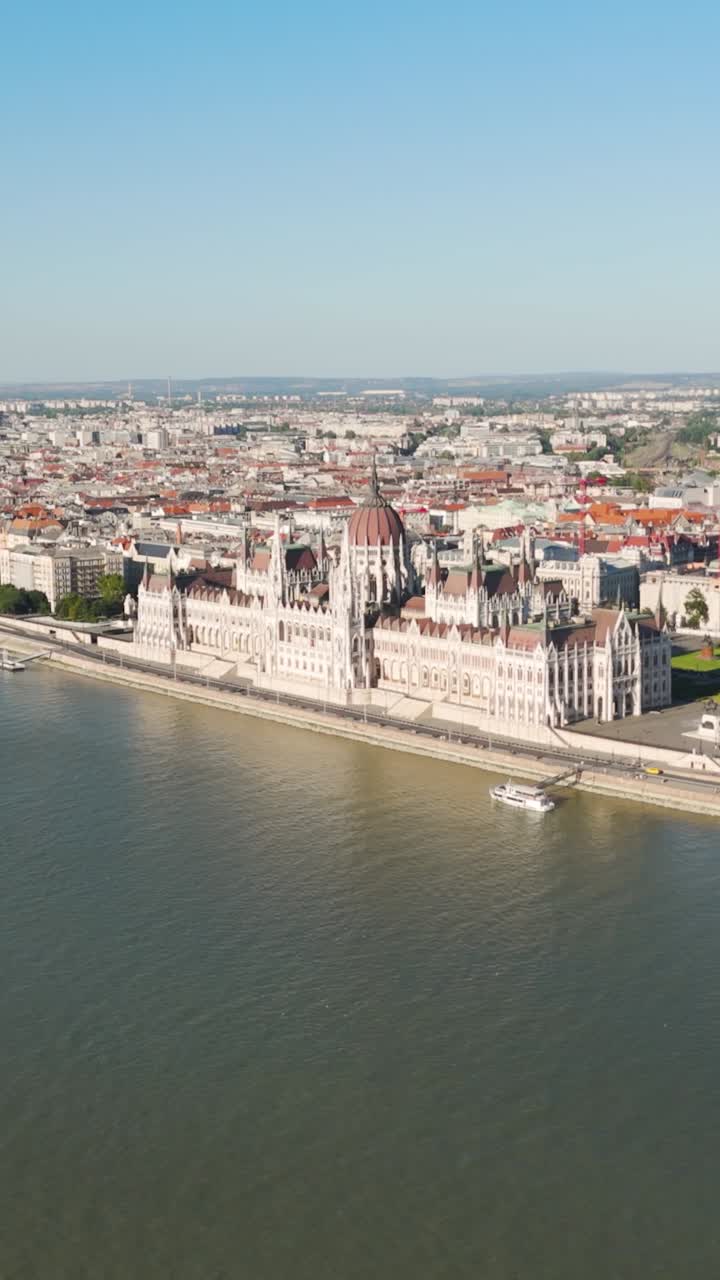Ripresa aerea verticale che si muove lungo il fiume Danubio, mostrando l'iconico Parlamento ungherese