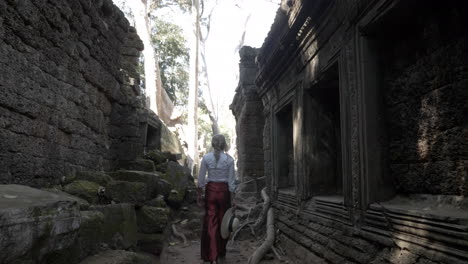 bella mujer caminando por las antiguas ruinas del antiguo templo de piedra en camboya