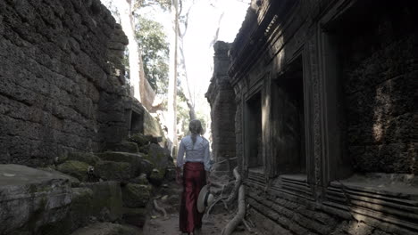 beautiful woman walking through ancient ruins of old stone temple in cambodia