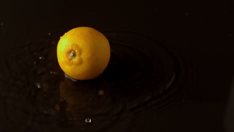 limón cayendo sobre una superficie negra y húmeda