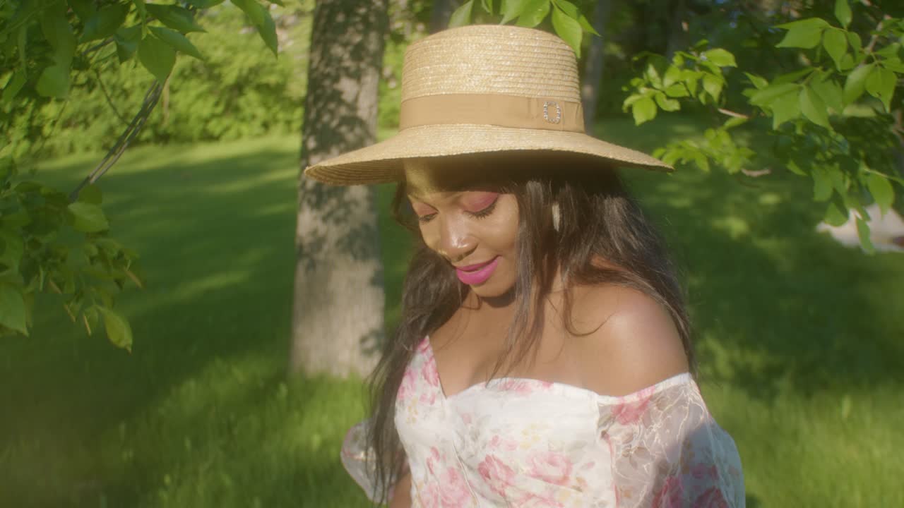 mujer negra con cesta de picnic ajustando el cabello en el parque dando vueltas