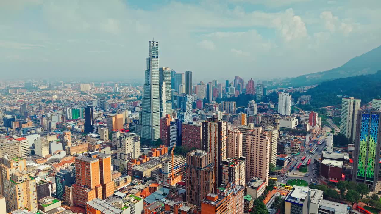 Aerial view dolly in of the Bacata tower and aerial perspective of the city of Bogota, Colombia on a sunny day with clouds in the background.