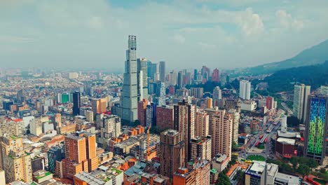 aerial view dolly in of the bacata tower and aerial perspective of the city of bogota, colombia on a sunny day with clouds in the background.