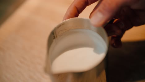 barista cools milk for coffee