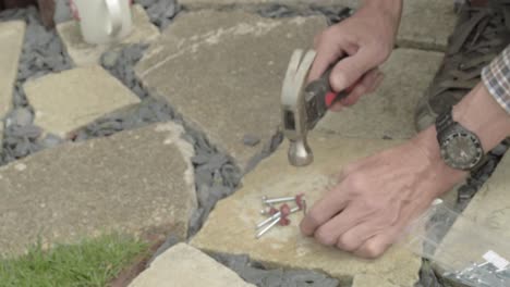 Manos-De-Trabajador-Martillando-Clavos-En-El-Clip-Del-Cable-Del-Gancho-De-Clavos-En-El-Piso-De-Concreto