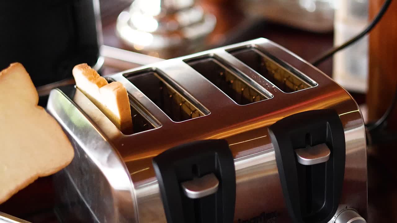 Hand placing bread slices into toaster slots