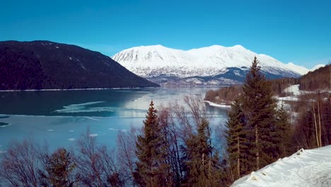 4k drone video of snow covered lakeside mountains in alaska during winter