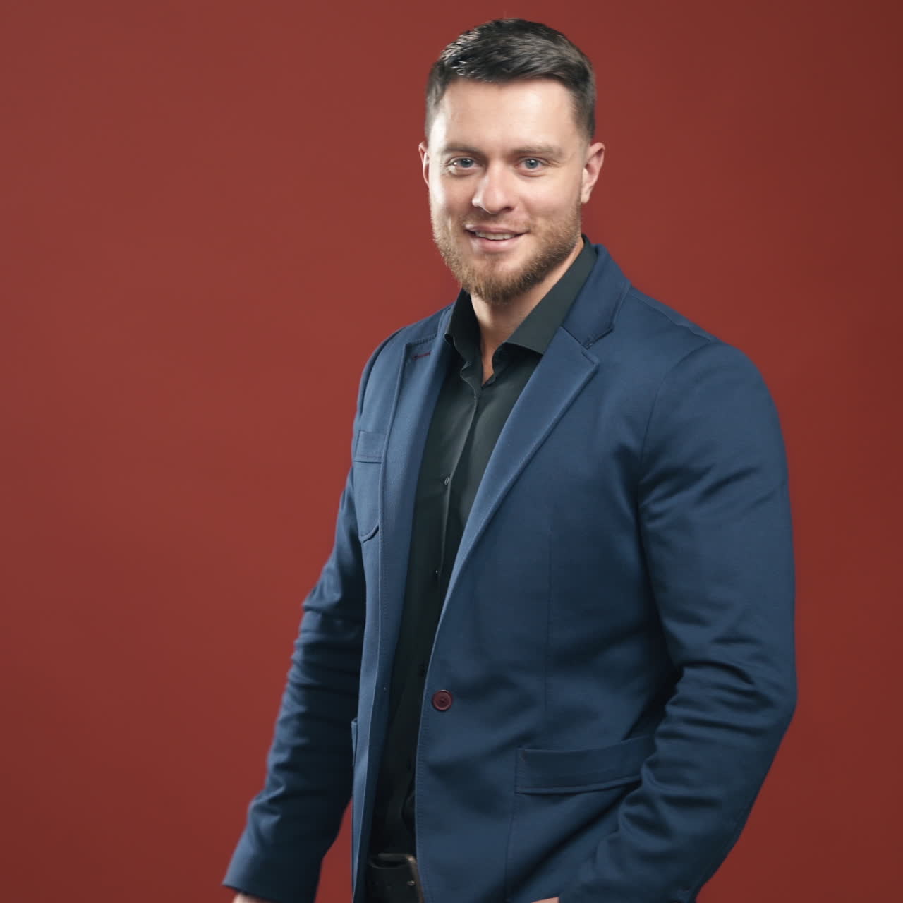 Portrait of handsome businessman. Stylish man taking off black glasses on the studio background. Smiling man in dark blue suit posing on camera.