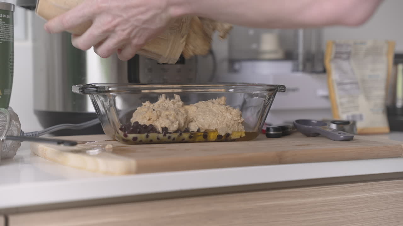 Clip of white man pouring vegan cake batter in a loaf pan, in a modern kitchen setting