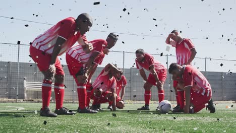 confetti falling against against team of male soccer players sitting in disappointment