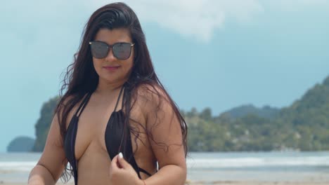 Hispanische-Latina-Spielt-In-Ihrem-Haar,-Während-Sie-Auf-Einem-Baumstamm-Am-Strand-Sitzt