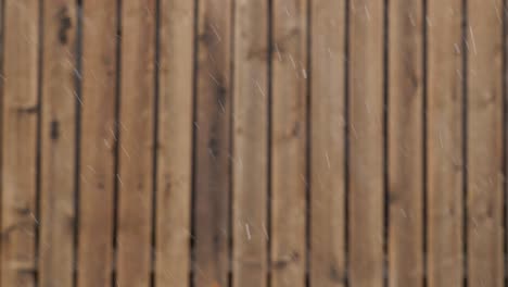 snow falling against a background of wooden fence