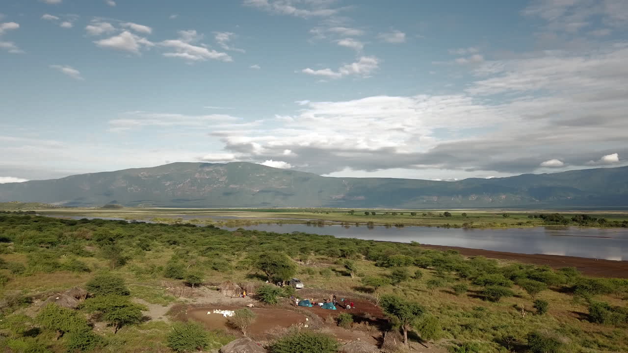 Splendida vista 4K con drone di un accampamento di Tanzaniani e turisti in una giornata di sole nella zona del Lago Natron in Kenya