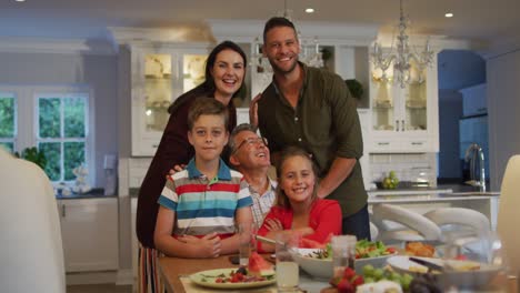 Portrait-of-caucasian-parents,-son,-daughter-and-grandfather-sitting-at-table-after-family-meal