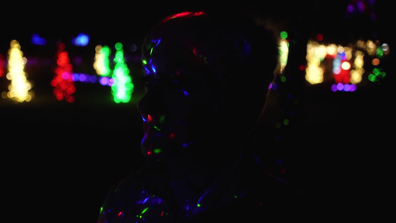 Woman with colorful Christmas laser lights on her face looking in wonderment