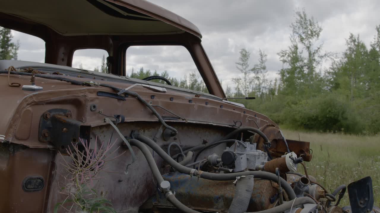 Abandonded rusted pickup truck in a grass field with engine missing