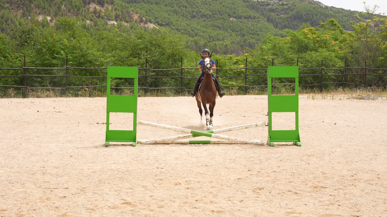 Horse and rider leap over a hurdle during show jumping practice in an outdoor equestrian arena
