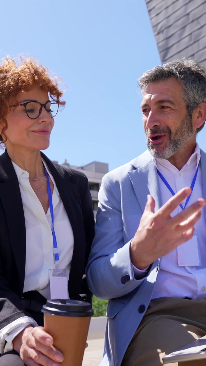 Professionisti che discutono di lavoro all'aperto con laptop e caffè