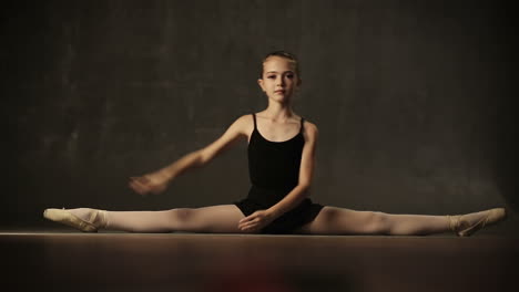 little adorable young ballerina in tutu and pointe in the black studio