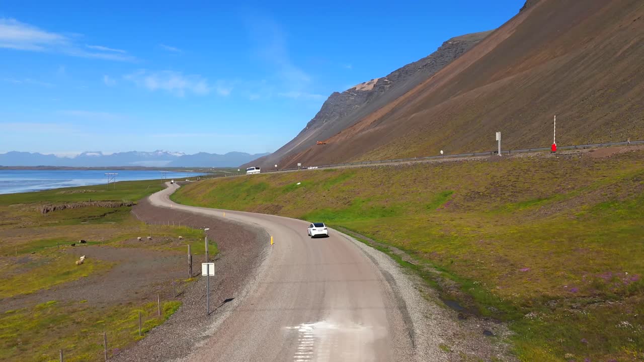 A Tesla car drives through Iceland’s winding roads, captured from the sky in a stunning drone shot of technology in nature.