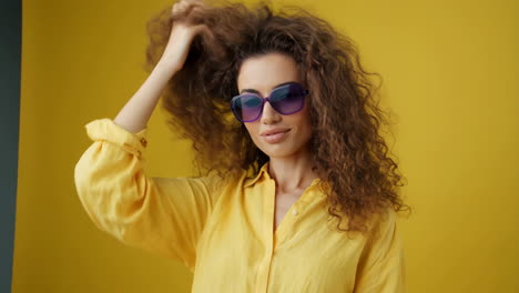 stylish woman with curly hair and purple sunglasses in yellow